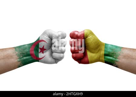 Due mani si pugno l'una all'altra su sfondo bianco. Bandiere di paese dipinte fisti, conflitto di crisi concetto tra algeria e Guinea Foto Stock
