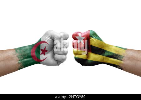 Due mani si pugno l'una all'altra su sfondo bianco. Bandiere di paese dipinte pugni, conflitto concetto di crisi tra algeria e togo Foto Stock