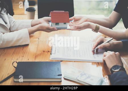 Giovane coppia decidere prima di firmare contratto di contratto e prezzo, mentre broker offrire prezzo esclusivo. Concetto di bene immobile. Foto Stock