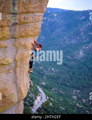 Un solo scalatore maschile sale su una ripida formazione rocciosa nelle montagne di Santa Catalina, Arizona. Foto Stock