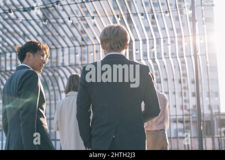 Gruppo di uomini d'affari che camminano nel quartiere degli affari. Giovani uomini e donne che parlano e discutono all'aperto Foto Stock