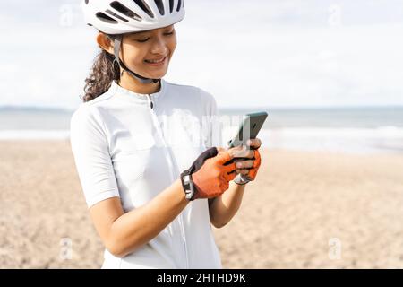 una ciclista femminile che guarda il suo smartphone dopo aver fatto un giro in bicicletta Foto Stock