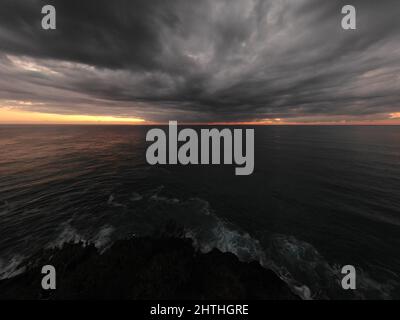 Ipnotizzante vista del Sunrise Cabarita Headland NSW Australia sull'acqua con le nuvole scure all'orizzonte Foto Stock