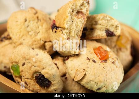 Biscotti appena sfornati con farinata d'avena morbida con uvetta, frutta candita, semi di lino e sesamo e noci in primo piano Foto Stock