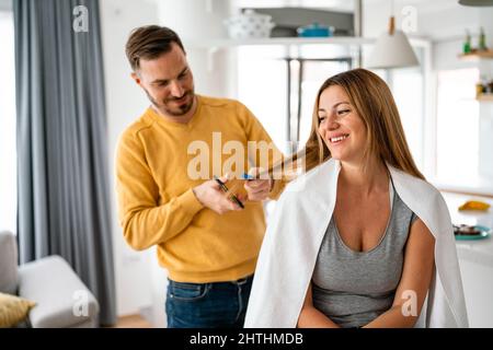 L'uomo fa un taglio di capelli alla donna a casa durante la quarantena. Foto Stock