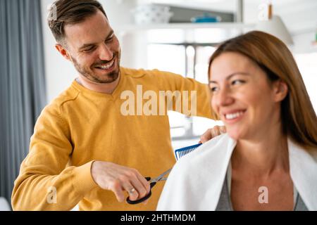 L'uomo fa un taglio di capelli alla donna a casa durante la quarantena. Foto Stock