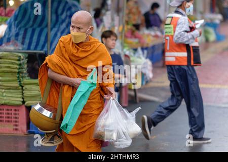 Un monaco in una strada a Bangkok, in Thailandia, che porta la sua ciotola di elemosina e il suo raggio di elemosina (donazione di cibo) raccolti durante il suo rito mattina elemosina ' round Foto Stock