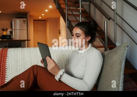 Studentessa caucasica seduta su allenatore che lavora su tablet digitale Foto Stock