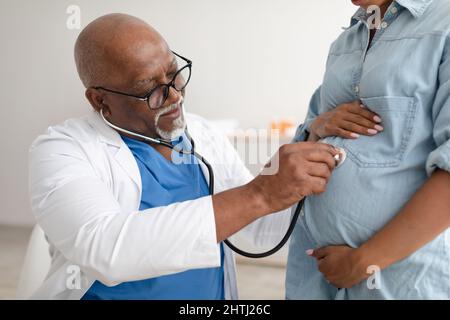 Uomo esperto medico che esamina giovane donna incinta Foto Stock