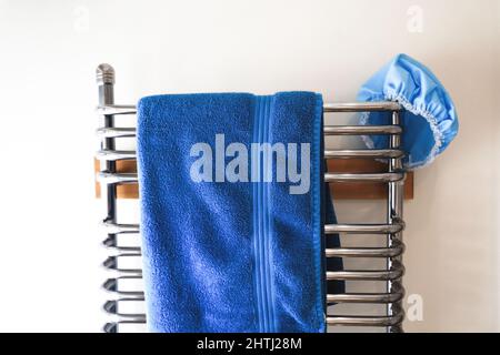 Asciugamano blu e tappo doccia, appesi su un radiatore a scala cromato. Foto Stock