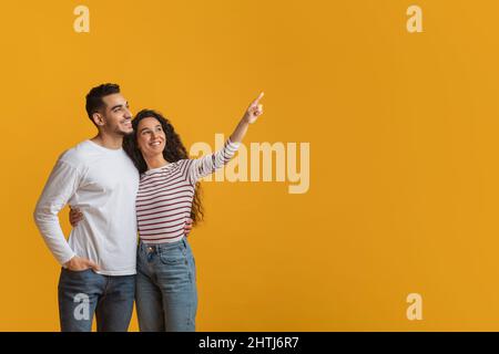 Controllare. Sorridente giovane coppia mediorientale che punta da parte a Copy Space Foto Stock