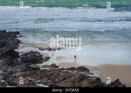 La piccola figura di persona che corre lungo la costa su una ventosa Fistral Beach a Newquay in Cornovaglia. Foto Stock