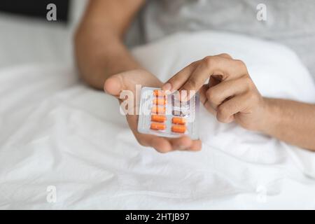 Sick Man Holding Blister Pack con pillole, prendendo Medicina a casa Foto Stock