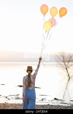 Un artista serio che suona uno strumento musicale a corde mentre pratica le abilità in piedi su sfondo bianco Foto Stock