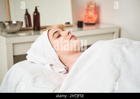Pieno corpo di positivo donna proprietario con bastone di legno giocando con cane nero sulla costa sabbiosa vicino al mare in resort tropicale Foto Stock