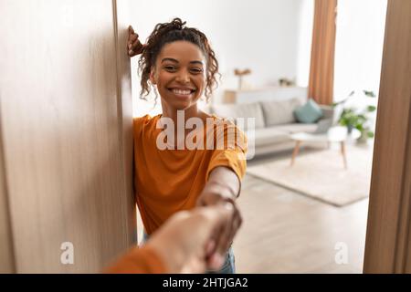 Allegra donna africana che agita le mani in porta aperta a casa Foto Stock