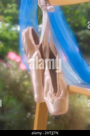 Scarpe da balletto rosa Satin Pointe che si aggettano sulla sedia in giardino erbaceo Foto Stock