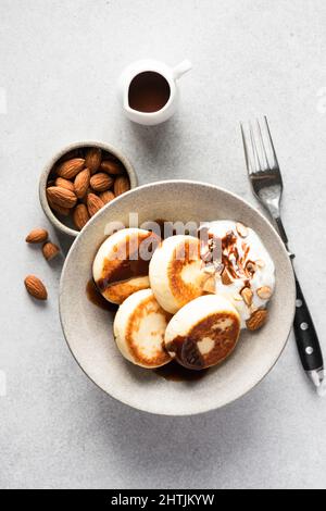 Frittelle di formaggio Syrniki con panna acida e salsa al cioccolato, sfondo grigio tavolo in cemento. Vista dall'alto Foto Stock