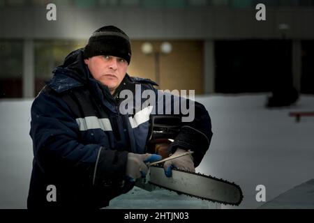 Un file manuale lavoratore acuisce una motosega catena Foto Stock