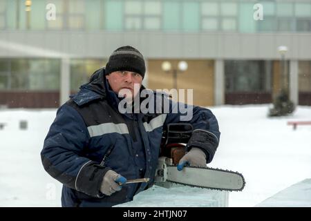 Un file manuale lavoratore acuisce una motosega catena Foto Stock