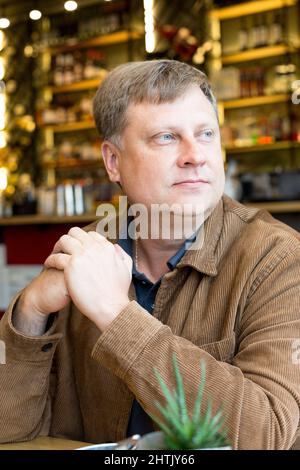 Un uomo cresciuto bionda 40-45 anni in un corduroy giacca seduto caffè a un tavolo. Foto Stock