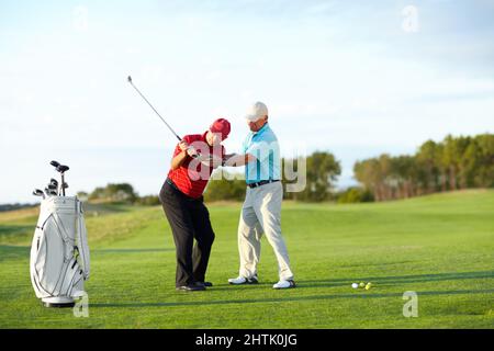 La tecnica corretta. Un golfer maschio che ottiene l'aiuto dal suo caddy sul campo da golf. Foto Stock