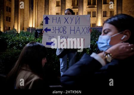 Georgia. 28th Feb 2022. A Tbilisi, un manifestante ha un segno davanti al Parlamento della Georgia il 5th giorno di proteste contro l'invasione russa dell'Ucraina. I segni indicano tre direzioni: Up è ''Vai all'inferno'', sinistra è ''e di nuovo all'inferno'', destra è ''tutto il senso alla Russia, vada all'inferno! (Credit Image: © Aurelien Foucault/ZUMA Press Wire) Foto Stock