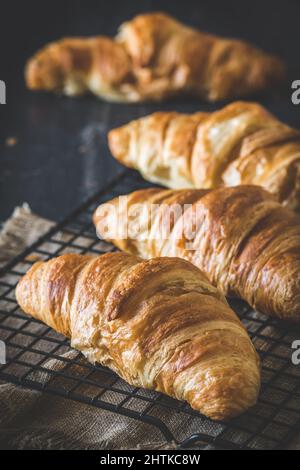 Fila di deliziosi croissant francesi su sfondo nero, verticale Foto Stock
