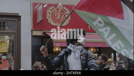 Londra, UK - 11 06 2021: Un uomo che indossa una maschera che tiene una bandiera palestinese su Strand Street per il COP26 “Giornata globale d’azione per la giustizia climatica”. Foto Stock