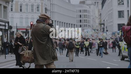 Londra, UK - 11 06 2021: Un fotografo su Fleet Street che scatta una foto di una folla di manifestanti sulla strada per Trafalgar Square, alle COP26. Foto Stock