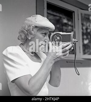 Riprese amatoriali nel 1940s. Una donna anziana usa una macchina fotografica, la tiene e la mira a qualcosa. Un'attrezzatura amatoriale per filmare film da vedere a casa. Svezia 1948 Kristoffersson Ref AL31-3 Foto Stock