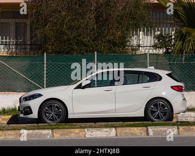 Side, Turchia – 13 2022 febbraio: Bianco BMW serie 1 è parcheggiata in strada in una calda giornata autunnale sullo sfondo di una strada Foto Stock