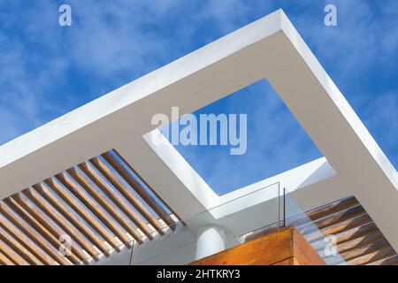 Astratto sfondo architettonico con angolo bianco di cemento e ombrellone in legno sotto cielo nuvoloso blu Foto Stock