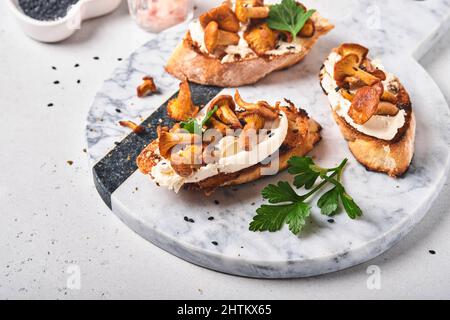 Panini con cravine al formaggio. Panino a faccia aperta con formaggio cremoso, condimenti e pepe e prezzemolo fresco su un vecchio sfondo di legno. Mock Foto Stock