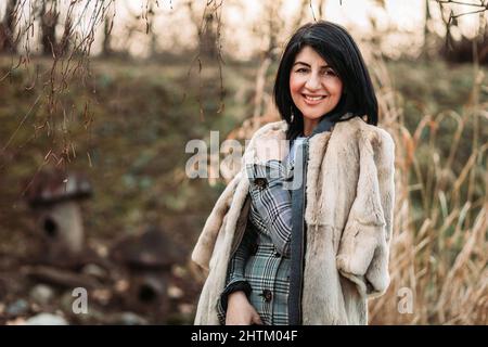 Donna moderna di mezza età in pelliccia di cappotto, sorridente Foto Stock