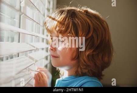 Concetto di Qarantine. Proteggetevi. Rimani a casa in isolamento. COVID-19 blocco. Bambino che guarda attraverso la finestra. Pandemia di coronavirus. Foto Stock