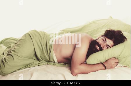 Ragazzo che dorme a letto con cuscini a casa. Bell'uomo a letto. Svegliati Sleepy. Foto Stock