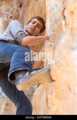 Arrampicatore di scogliera. Ritratto di un giovane scalatore di roccia su una rockface di arrampicata. Foto Stock