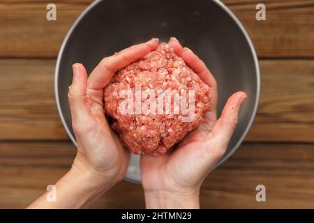 Carne macinata cruda in snella vista dall'alto delle mani della donna Foto Stock