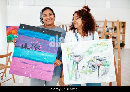 Siamo orgogliosi artisti. Ritratto ritagliato di due giovani donne attraenti in piedi insieme e tenendo la loro opera dopo una classe d'arte in studio. Foto Stock