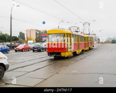 Trasporti pubblici a Kiev (Kiev), capitale dell'Ucraina: Un tram rosso e giallo (tram) in una strada nel centro della città in una giornata opaca e umida Foto Stock