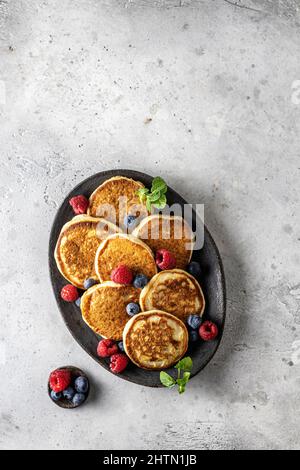 Pancake in piastra di ceramica con frutti di bosco, foglie di menta e barca con sugo di carne, vista dall'alto Foto Stock