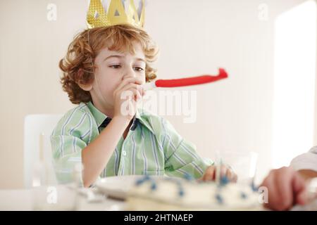 Inizia questa festa. Scatto di un ragazzo di compleanno che soffia un corno da festa. Foto Stock