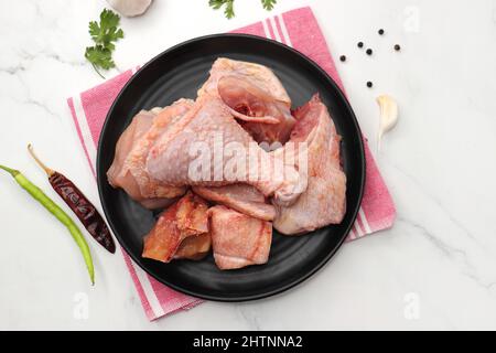 Pollo pulito e crudo su un piatto nero con spezie indiane e ingredienti da cucina. Insieme allo spazio di copia. Taglio di curry di pollo. Pollo tagliato Biryani Foto Stock