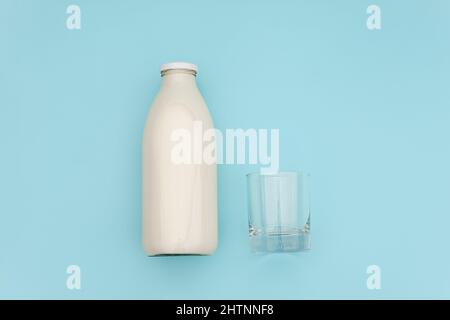 Latte in bottiglia di vetro e vetro vuoto su sfondo blu con spazio per la copia. Vista dall'alto Flat Lay. Foto Stock