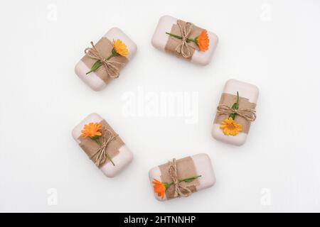 Set di sapone naturale fatto a mano decorato con carta artigianale, fiori di calendula arancione su sfondo bianco. Concetto di cosmetici biologici. Vista dall'alto, temp. Posa piana Foto Stock