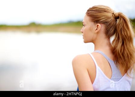 È tutto su come trovare la calma nel caos. Scatto retroguarato di una giovane donna seduta all'aperto. Foto Stock