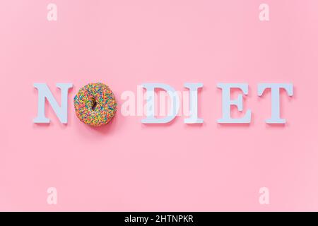 Testo Nessuna dieta dalle lettere bianche del volume e dalla ciambella colorata glassata su sfondo rosa. Concept International No Diet Day, 6 May Top View Flat Lay Templa Foto Stock