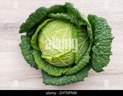 Cavolo verde isolato su sfondo di legno. Cibo vegetariano fresco e sano Foto Stock
