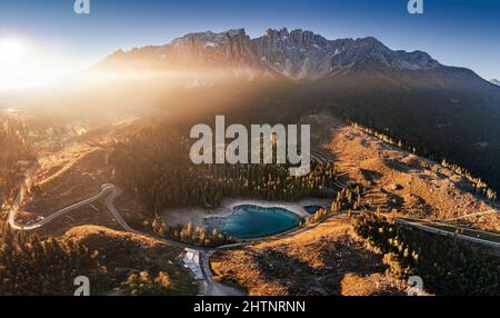 Carezza, Italia - veduta panoramica aerea delle Dolomiti italiane con il Lago Carezza (Lago di Carezza) e il Monte Latemar sullo sfondo di un autu soleggiato Foto Stock